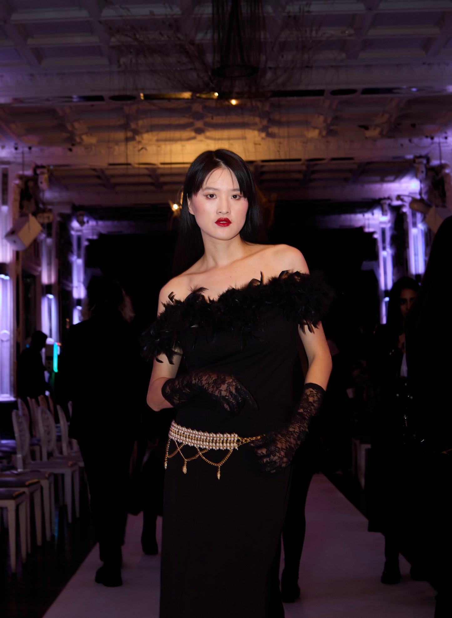 VOLIÀ Atelier - exclusively pre-loved. The gold and pearl chain belt Colette paired with black feather top Ines and a black maxi skirt for a stylish sleek look. Shop sustainable fashion at VOLIÀ Atelier today.