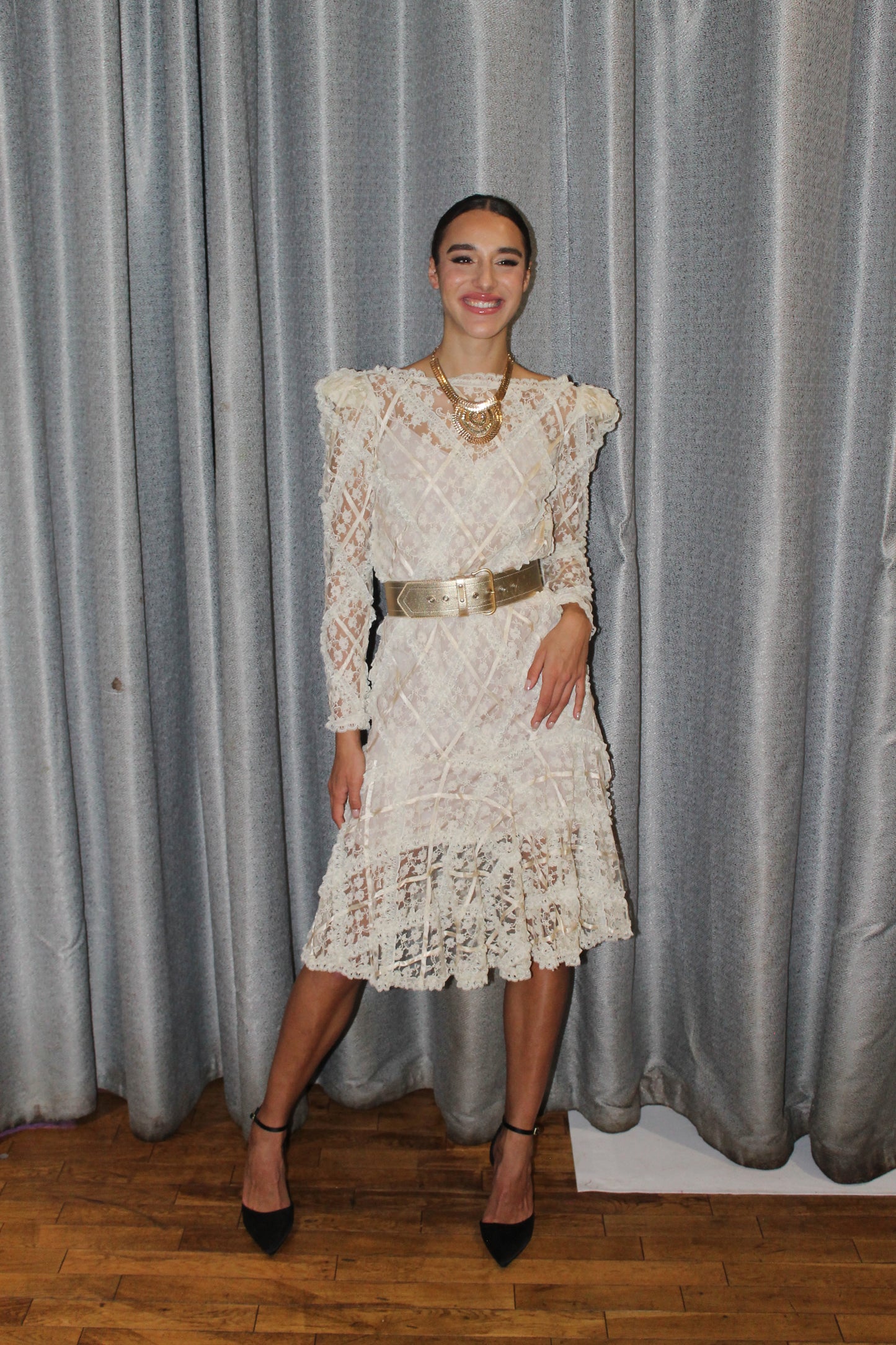 VOLIÀ Atelier - midi white ivory lace dress with long sleeves paired with a wide gold belt and gold statement necklace.